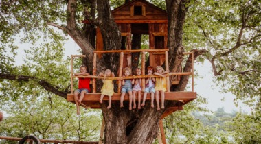 dzieci siedzące w domku na drzewie
